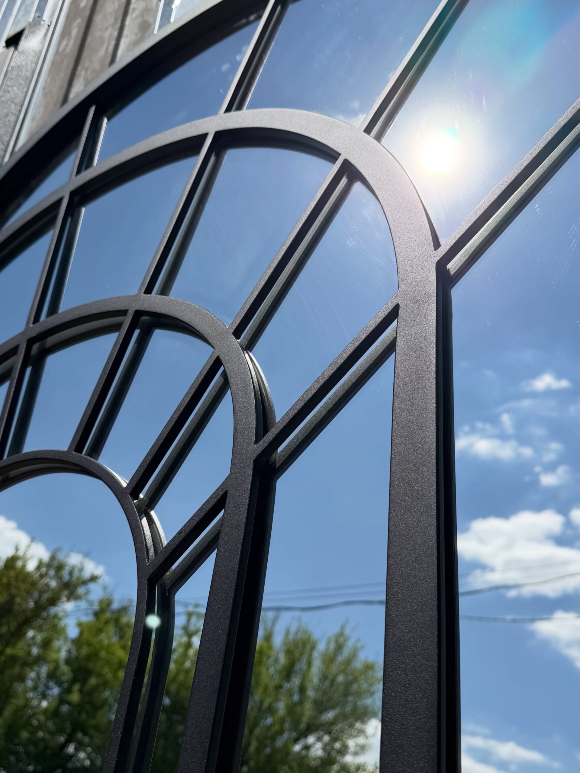 Black steel framed decorative mirror with ornamental detailing